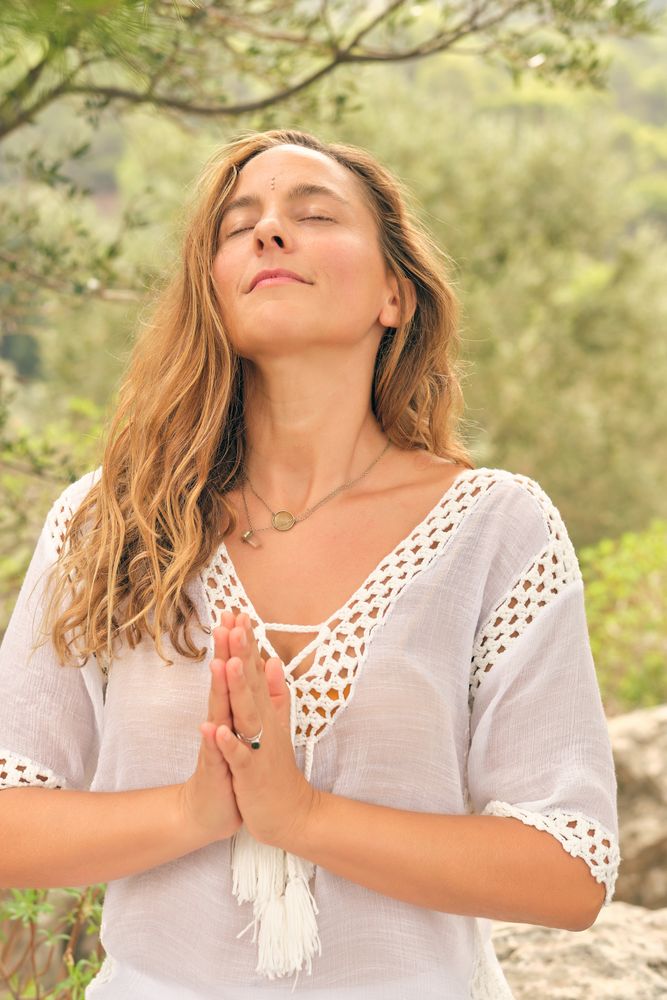 Peaceful woman with namaste hands in nature