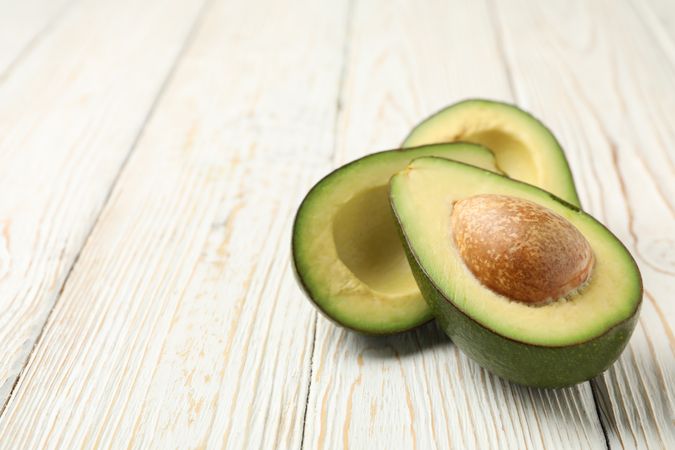 Ripe fresh avocado on wooden background, close up