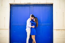 Amorous couple standing against blue door
