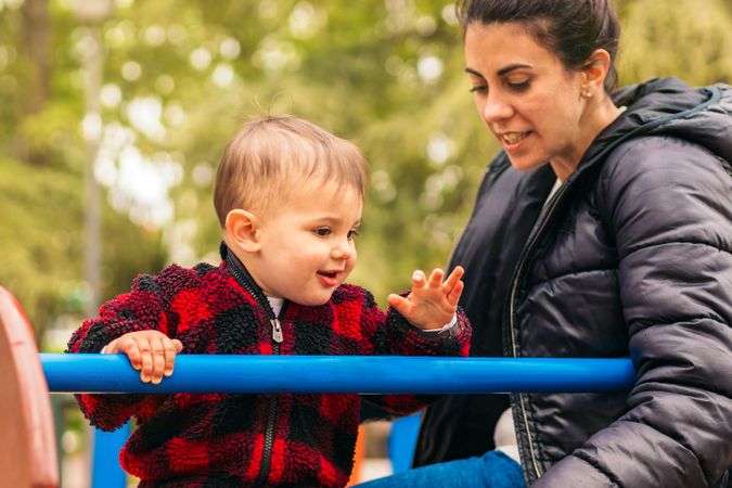 smiling mother and baby playing in a playground