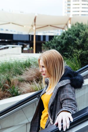 Blonde woman going down escalators