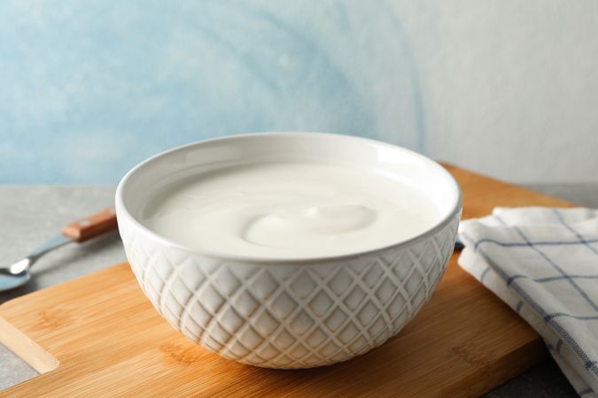 Composition with yogurt in bowl on grey table against blue background