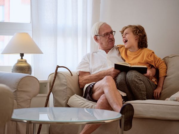 Laughing boy with grandfather reading book