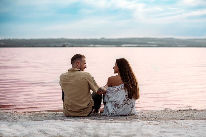 adorable couple sitting on an amazing beach with pink water