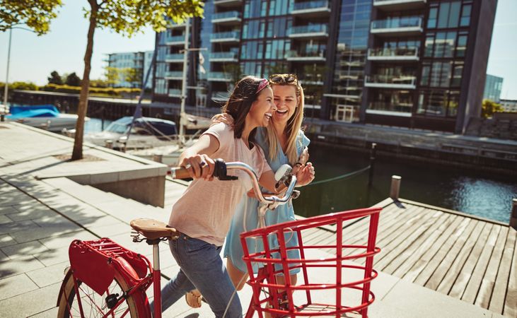 Two close friends laughing while walking and talking along the waterfront