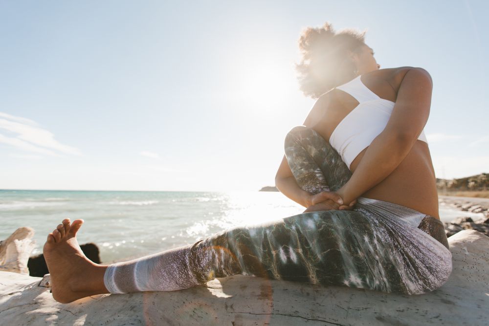 Sportive woman performing yoga posture on stones in nature