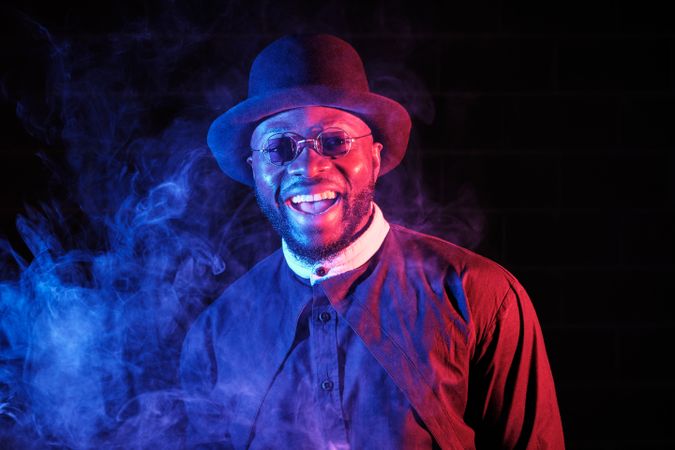 Cheerful Black man in darkness with fume