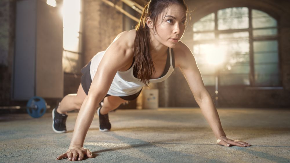 Athletic Beautiful Woman Does Push-ups as Part of Her Cross Fitness, Bodybuilding Gym Training Routine.