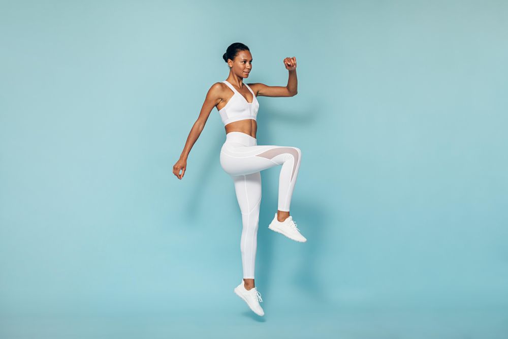 Sports woman jumping in blue studio