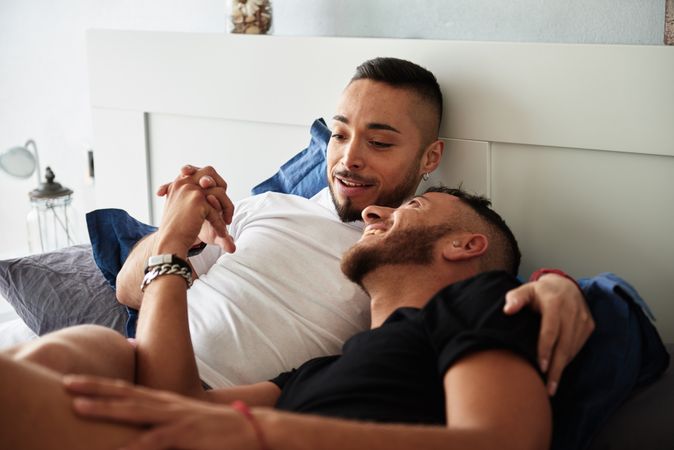 Smiling gay couple hugging on bed