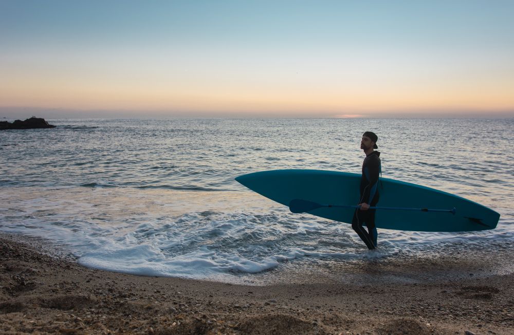 Man practicing paddle surfing with neoprene in a sunrise