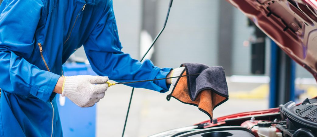 Banner of gloved hand of repairman checking oil of car engine