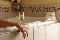 Woman Relaxing in the Bathroom Spa Tub with a Glass of Sparkling Champagne and Candles.