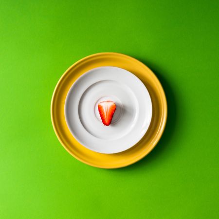 Strawberry half on plate setup on green background