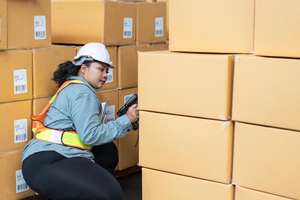 Woman in safety gear working in warehouse full of stock