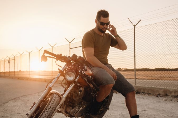 Man sitting on motorcycle and surfing mobile