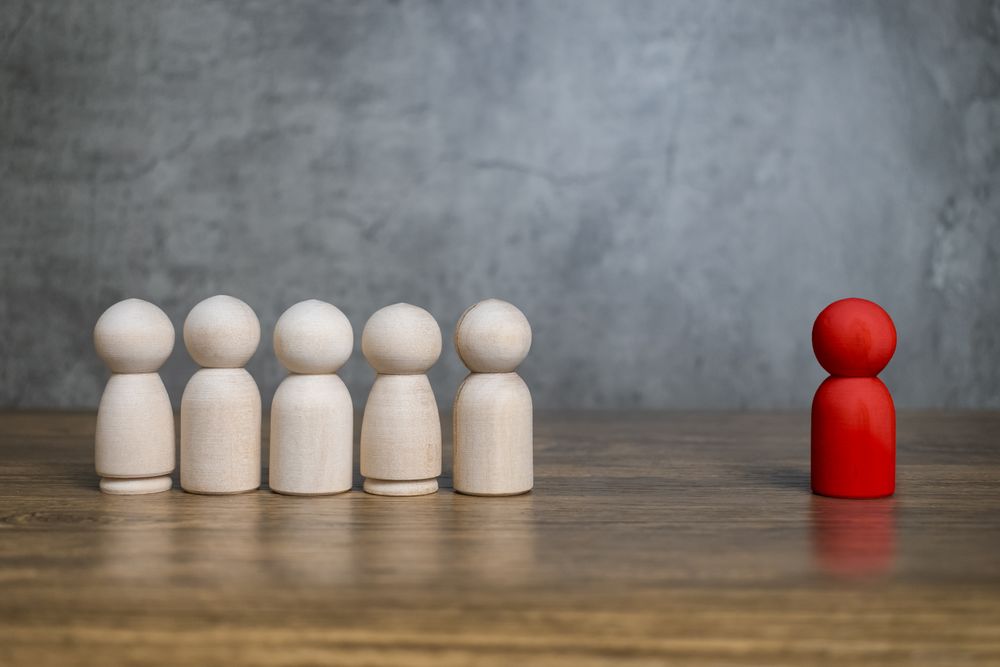 red wooden figure stand to the wooden group crowd. leadership and teamwork concept