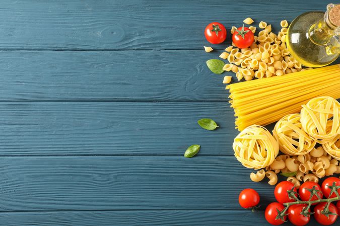 Composition with pasta ingredients on wooden background, space for text and top view