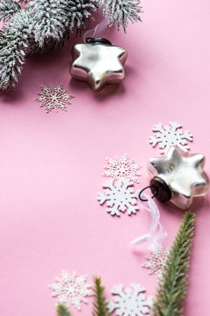 Silver star Christmas decorations and snowflakes on pink background with copy space
