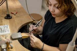 Focused adult craftswoman working in jewelry atelier