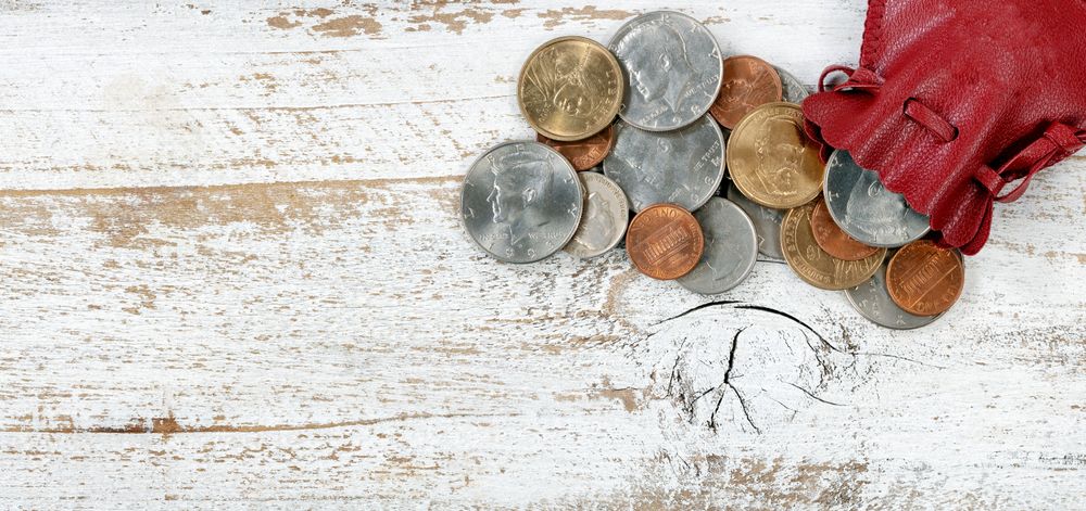Filled leather bag of United States coins on rustic wood