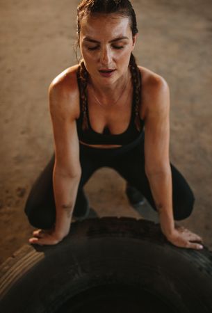 Female sitting by a huge tire taking rest after exercising