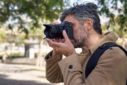 Man taking pictures on photo camera in city