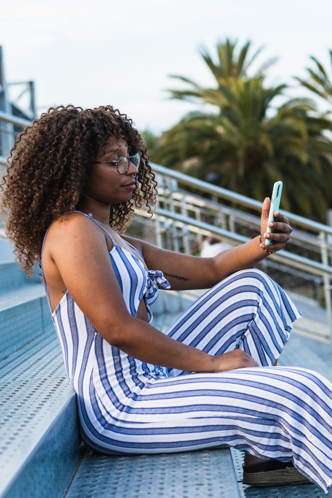 Stylish Black woman taking selfie on street