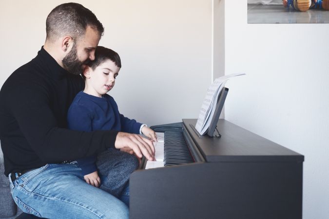 Father teaching son to play piano