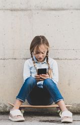 Kid using mobile phone with skate