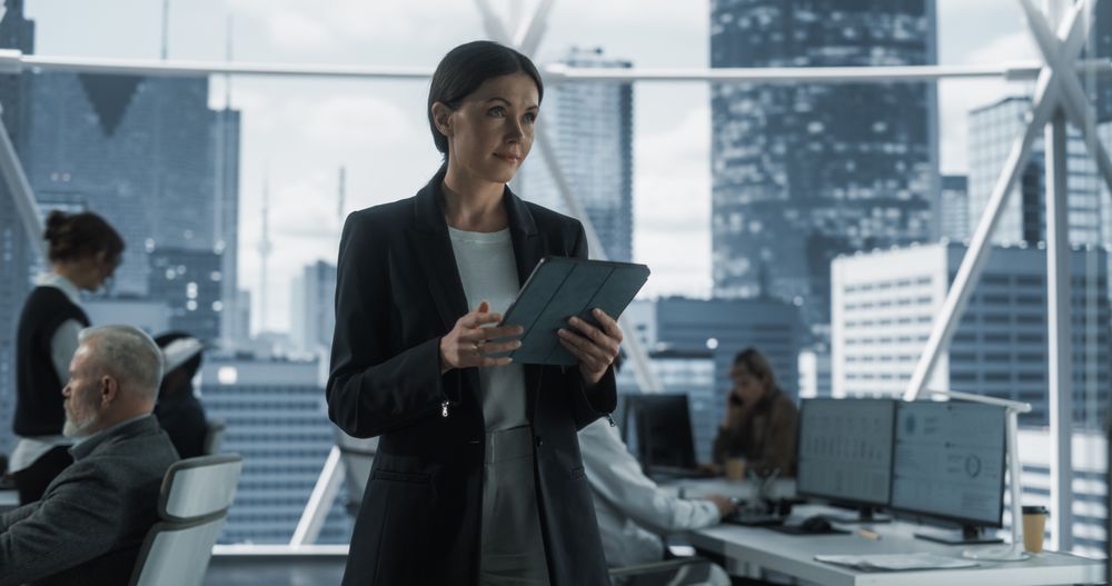 Successful Businesswoman Using Tablet Computer, Standing in Modern Diverse Office in Downtown And Working on Financial, Business and Marketing