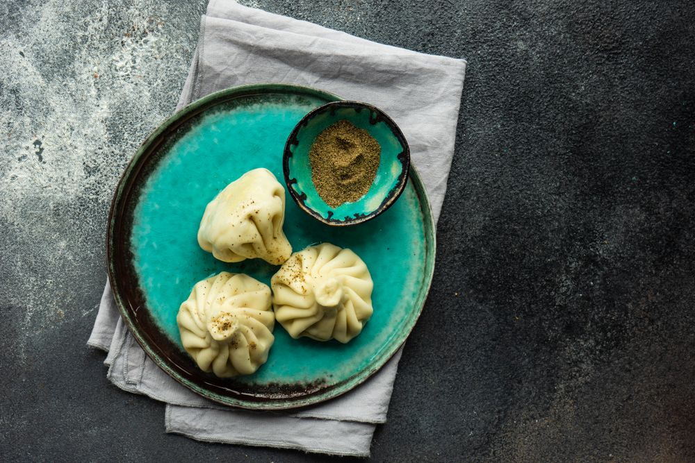 Teal plate with three Georgian khinkali dumplings with copy space