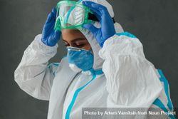 Side view of Black female medical worker adjusting her PPE goggles 4Bo8kb
