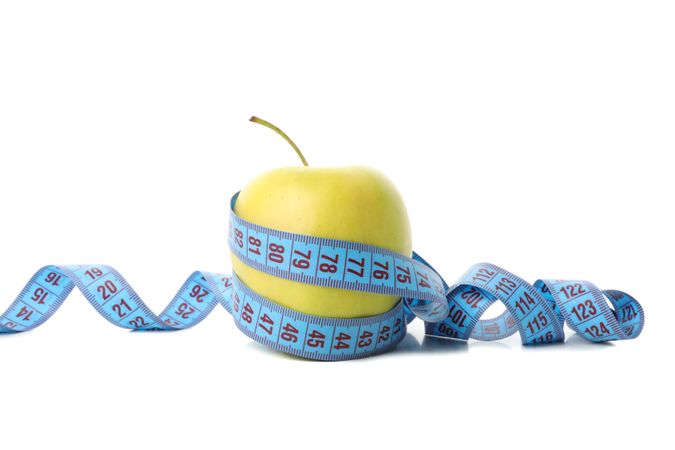 Measuring tape with apple isolated on light background