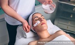Female resting in spa while having a clay mask applied 0KMaED