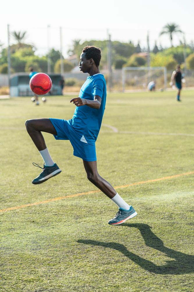 Black teenager juggling football ball