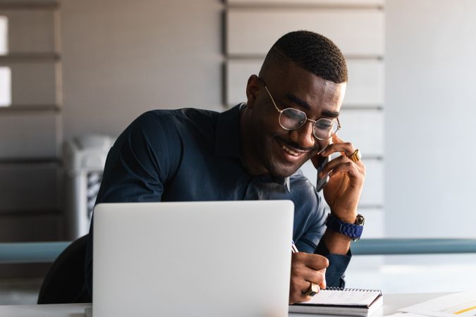 Black man talking on phone near laptop in office