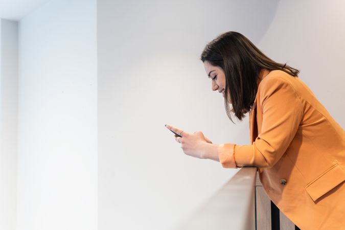 Delighted woman browsing smartphone in office