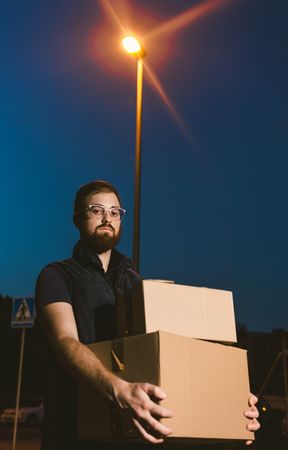 Courier delivering cardboard boxes in evening