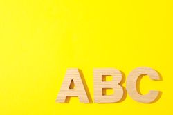Wooden letters of English alphabet on color background, space for text