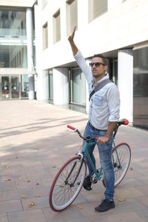 Male sitting on colorful bike with one arm up