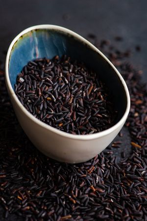 Organic dark rice in ceramic bowl on kitchen counter