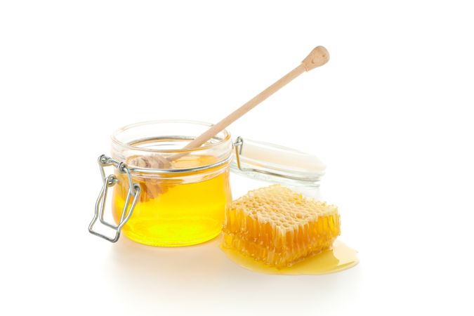 Glass jar, honeycomb and dipper isolated on neutral background