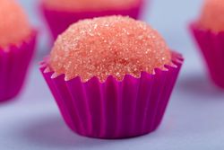 Close up of pink strawberry truffles with sugar on blue table