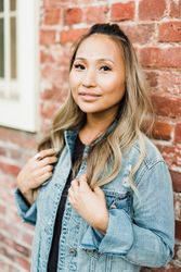 Woman in blue denim jacket leaning on a wall
