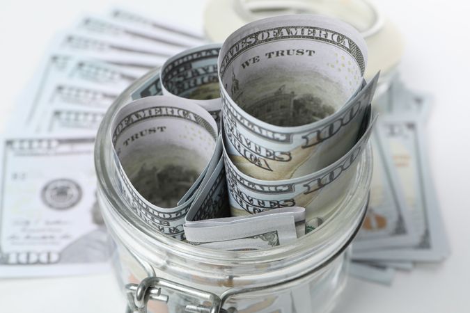 American cash money in glass jar on light background, close up