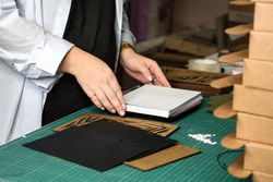 Female hands weigh stack of sheets of white paper before perforating it to create notepad