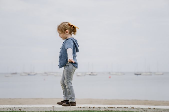Girl balancing on border near sea