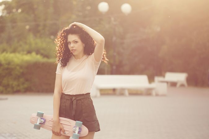 Female teenager with skateboard in park with light flare