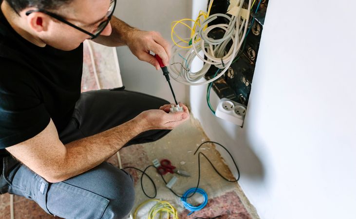 Technician with screwdriver and terminal strip installing telecommunication box